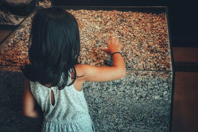 Rear view of girl touching resin in glass box at museum