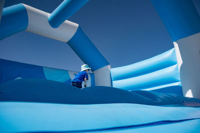 Boy in bouncy castle against clear blue sky