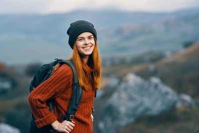Portrait of smiling young woman standing outdoors during winter