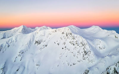 Scenic view of snow covered mountains against sky during sunset