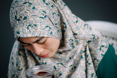 Close-up of woman wearing hijab while looking in jar