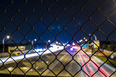 Close-up of chainlink fence against sky in city