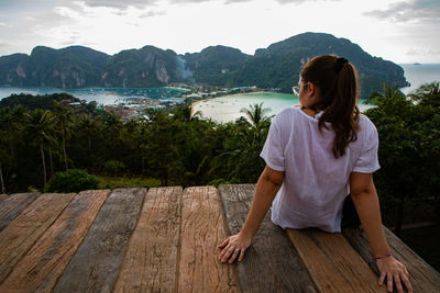 Rear view of woman sitting at observation point against sea