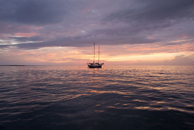 Boat sailing in sea against cloudy sky