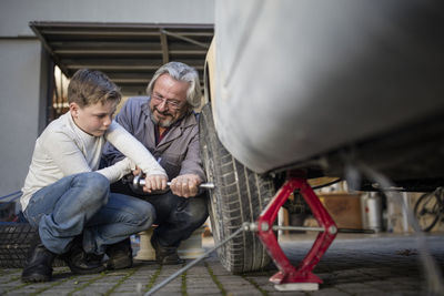 Senior man and boy changing car tire