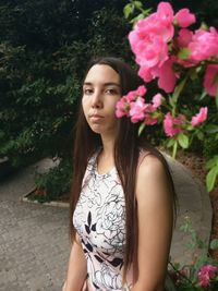 Portrait of beautiful woman standing by pink flowers in park