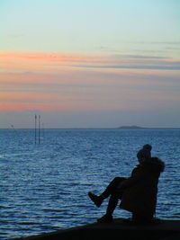 Silhouette man looking at sea against sky during sunset