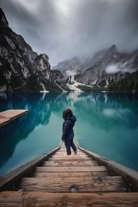 High angle view of woman standing on steps by lake against mountains