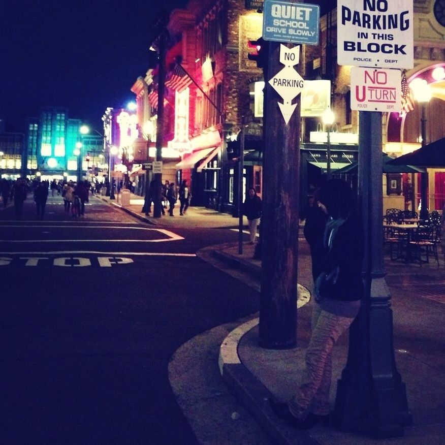 night, illuminated, text, building exterior, city, street, architecture, built structure, city life, western script, men, communication, person, non-western script, city street, incidental people, large group of people, road, store