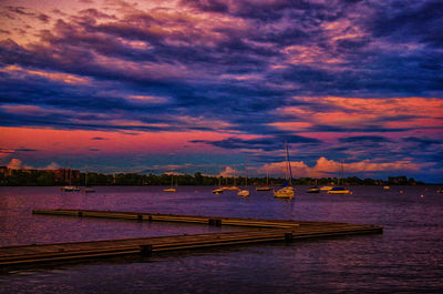 Boats moored at harbor during sunset