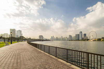 View of buildings by river against cloudy sky