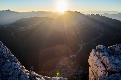 Sunlight streaming through rocks against sky during sunset