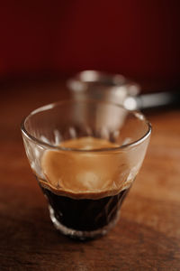 Glass cup of espresso coffee with crema on wooden table