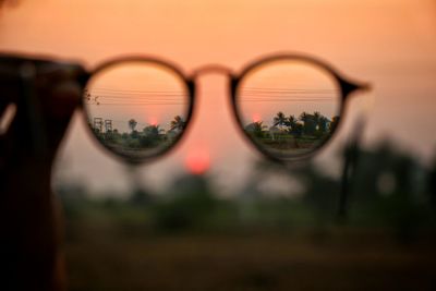 Close-up of sunglasses on glass during sunset