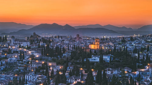 High angle view of illuminated cityscape against sky at sunset