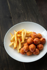 Spicy coated meatballs with spicy sauce served with fried potatoe fries. korean style snacking.