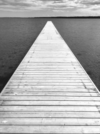 Wooden pier over sea against sky