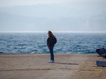 Woman looking away while standing against sea