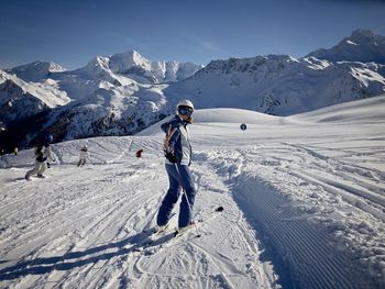 Man skiing on snow covered mountain against sky