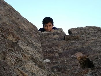 Portrait of young woman standing on rock against clear sky