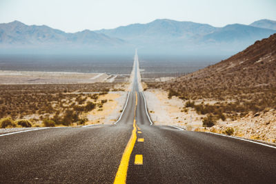 Road leading towards mountains against sky