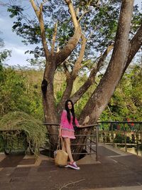 Full length of woman standing by tree against plants