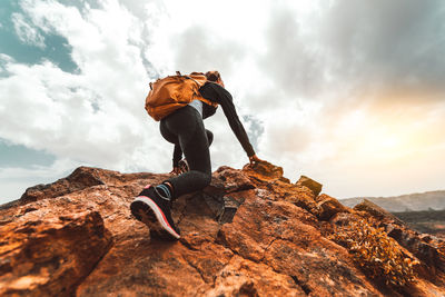 Low angle view of woman climbing on cliff