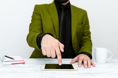 Midsection of businessman holding book while standing against white background