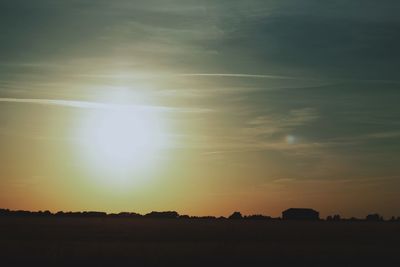 Scenic view of silhouette field against sky at sunset