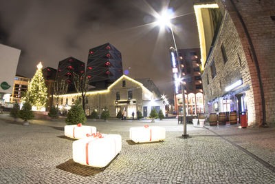 Street lights on footpath amidst buildings in city at night