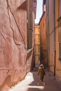 Rear view of girl walking on steps amidst buildings