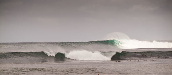 Waves splashing on shore against sky