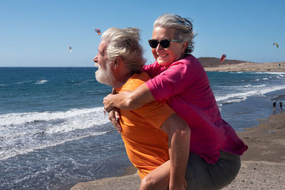 Senior man carrying woman piggyback at beach