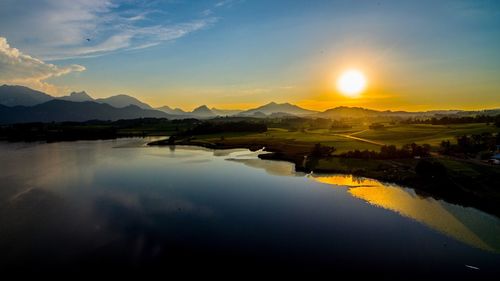 Scenic view of lake against dramatic sky at sunset