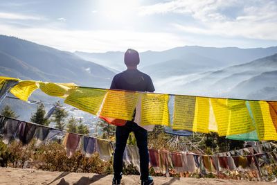 Rear view of man looking at mountains against sky