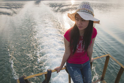 Young woman standing by sea