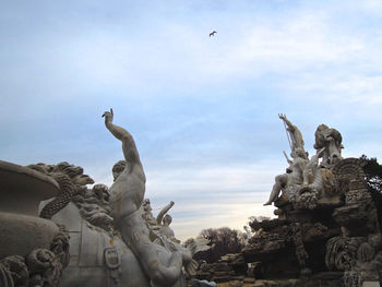 Low angle view of angel statue against cloudy sky