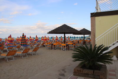 Chairs and tables on beach against sky