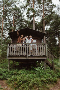 Friends taking selfie with mobile phone while in porch against house