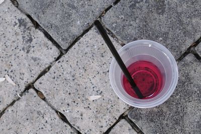 Directly above shot of drink in disposable glass on footpath