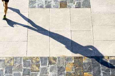 Shadow of athlete walking on footpath