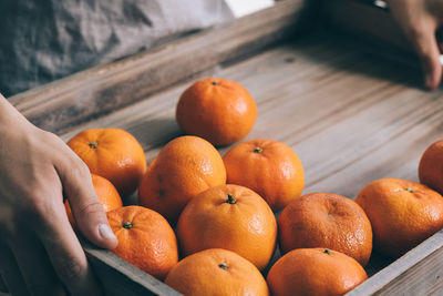 Man holding tangerines on a wooden tray