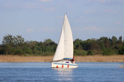 Sailboat sailing on lake against sky