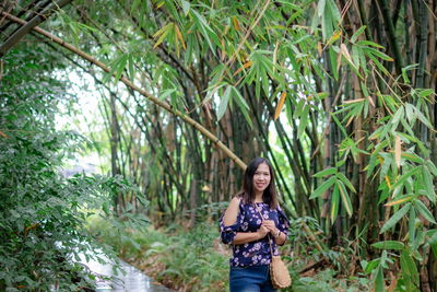 Portrait of smiling young woman against bamboo grooves