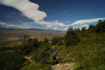 Full length of woman hiking amidst plants