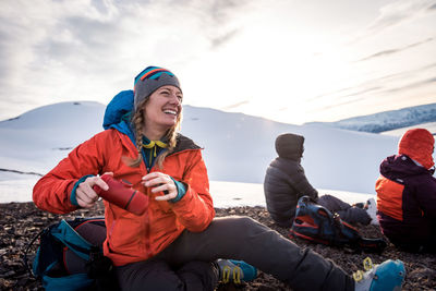 Woman laughing with coffee maker while outside in iceland snow
