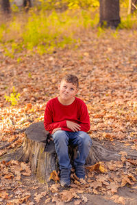 Full length of boy sitting on land during autumn