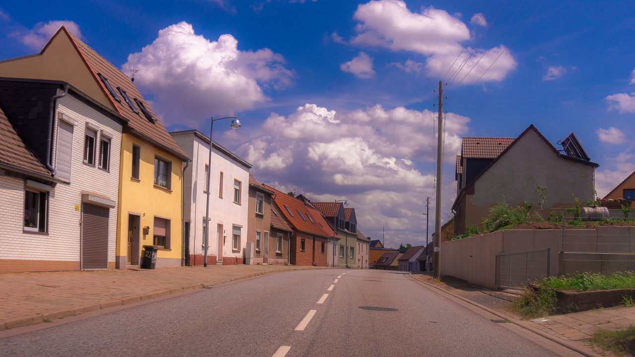 STREET AMIDST HOUSES AGAINST SKY