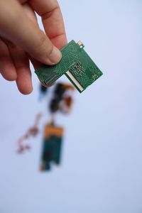 Cropped hand of person holding gift box against blue background