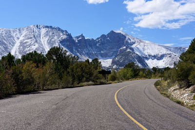 Road amidst trees and mountains against sky